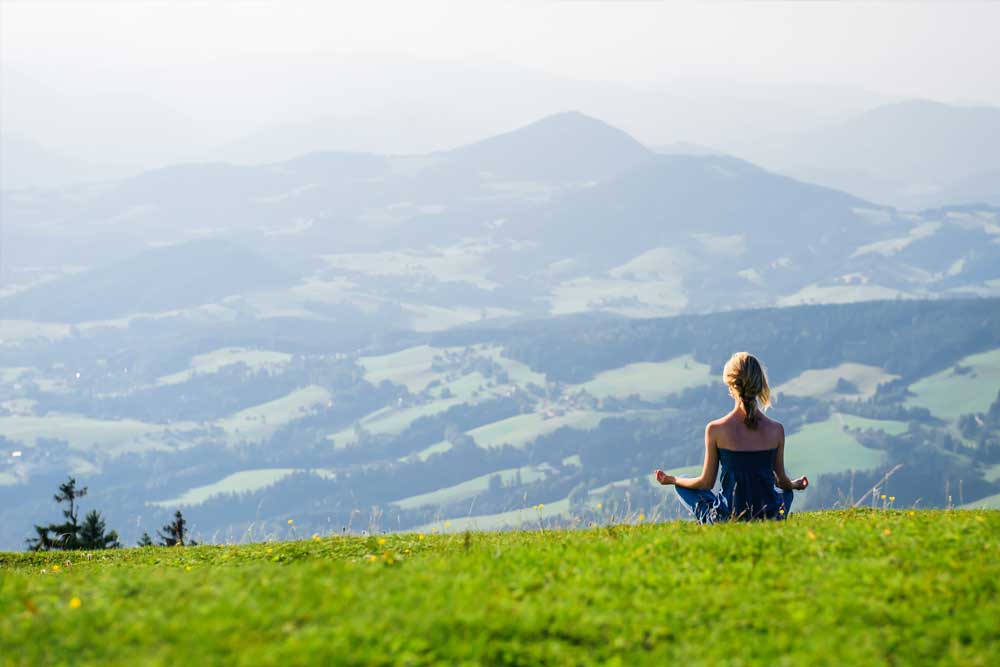 A woman sitting on top of a green hill.
