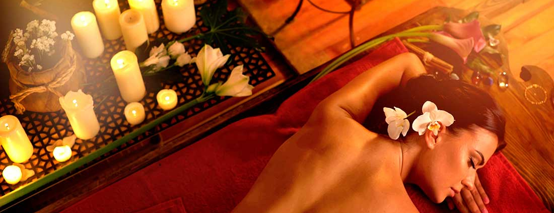 A person laying on the bed with candles in the background.